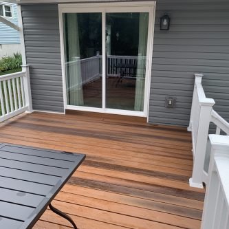 Deck with polished wood flooring and modern railing, adjacent to sliding glass doors, showcasing a home renovation by E-Stern Construction in Northeastern Pennsylvania.